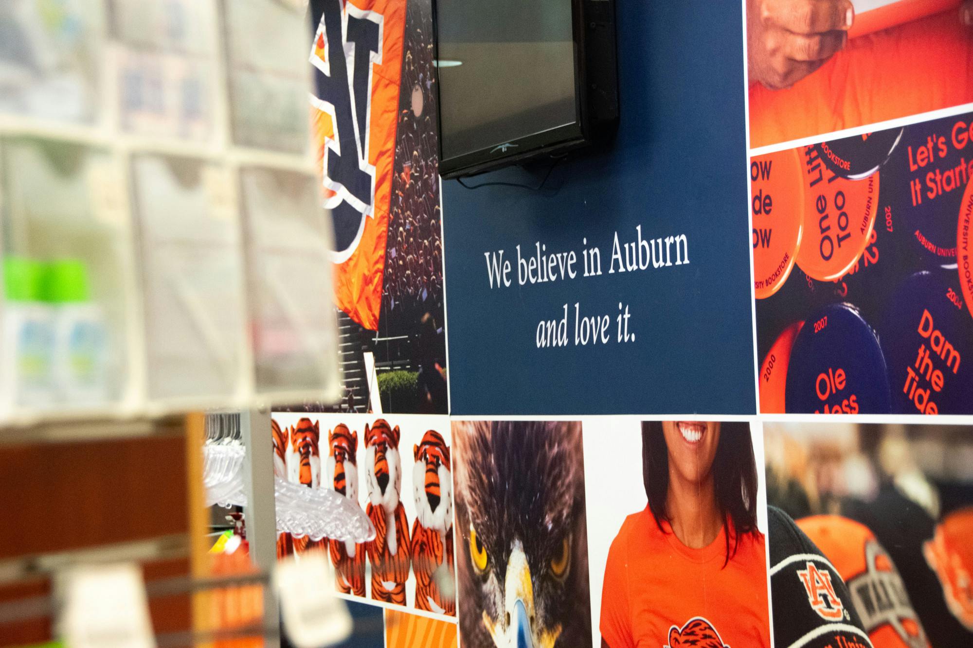 A wall displays a mix of photographs, graphics, and a quote celebrating Auburn University and its community spirit.