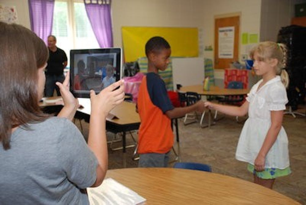 Graduate student Lacey Faciane uses an iPad 2 to record a "social story'' acted out by two children during summer program.( Contributed by AU News)