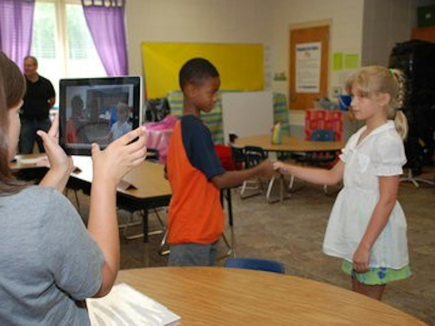Graduate student Lacey Faciane uses an iPad 2 to record a "social story'' acted out by two children during summer program.( Contributed by AU News)