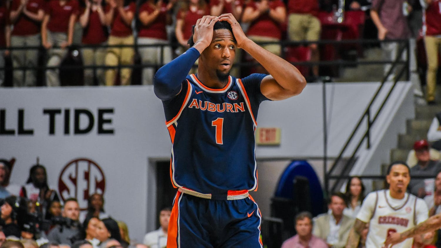 A player in an Auburn basketball uniform looks distressed, while a crowd in the background shows excitement.