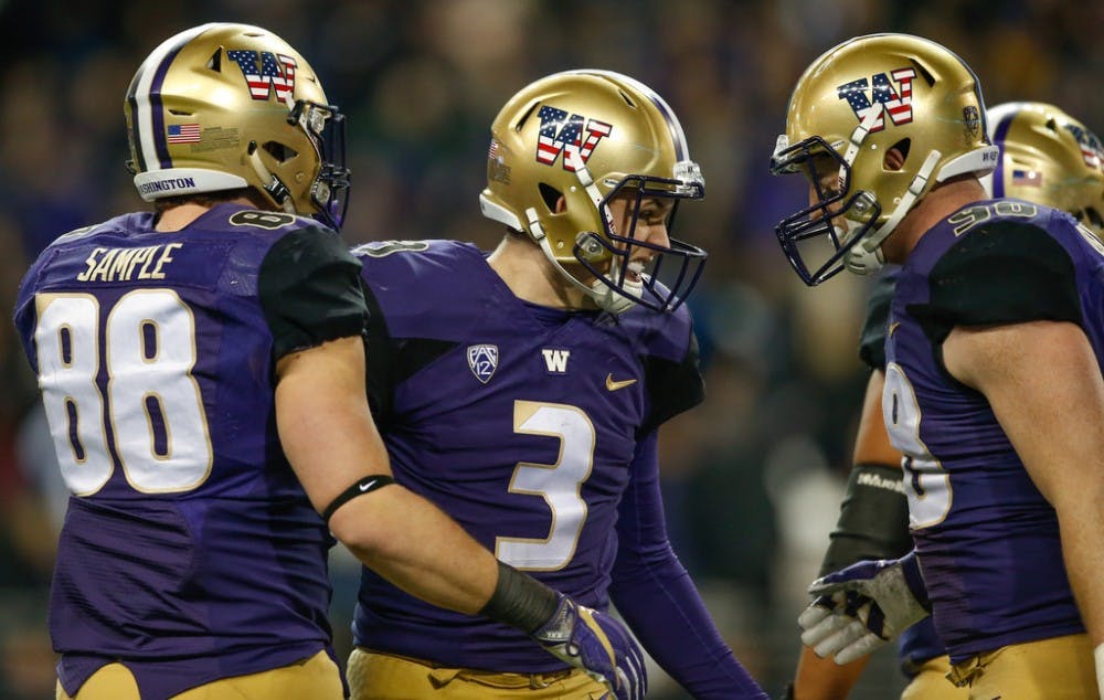 Quarterback Jake Browning #3 of the Washington Huskies is congratulated by tight end Drew Sample #88 and tight end Will Dissly #98 after throwing a touchdown pass to running back Lavon Coleman against the Utah Utes at Husky Stadium on November 18, 2017 in Seattle, Washington. The touchdown pass gave Browning 76 for his career, setting the school record.