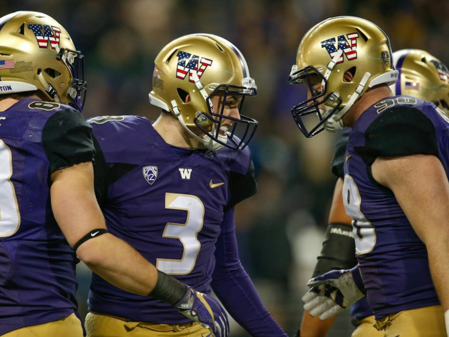 Quarterback Jake Browning #3 of the Washington Huskies is congratulated by tight end Drew Sample #88 and tight end Will Dissly #98 after throwing a touchdown pass to running back Lavon Coleman against the Utah Utes at Husky Stadium on November 18, 2017 in Seattle, Washington. The touchdown pass gave Browning 76 for his career, setting the school record.