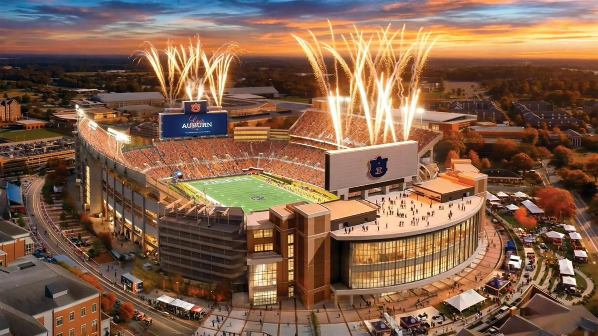 A large stadium filled with people celebrates with fireworks above, surrounded by an urban landscape at sunset.