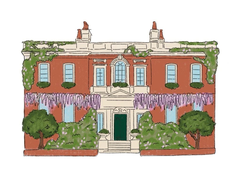 <p>A two-story red brick house is surrounded by lush green plants and wisteria flowers, featuring decorative windows and a central doorway.</p>