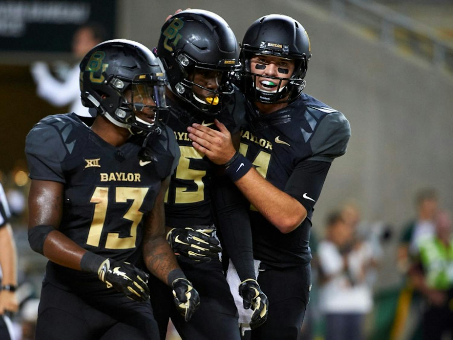 Denzel Mims #15 of the Baylor Bears celebrates after scoring a touchdown with teammates Tony Nicholson #13 and Zach Smith #11 against the Oklahoma Sooners during the second half at McLane Stadium on September 23, 2017 in Waco, Texas.