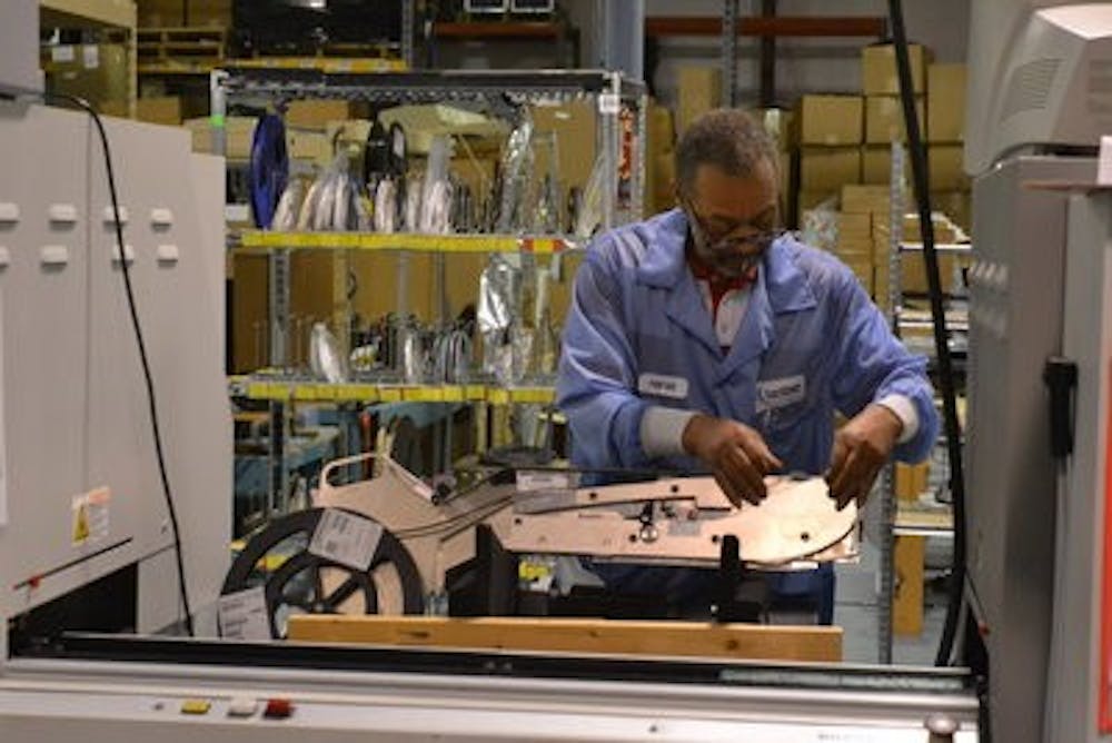 Harold Marshall, surface-mount technology operator, continues his work on manufacturing circuit boards for CoachComm. (Danielle Lowe / PHOTO EDITOR)