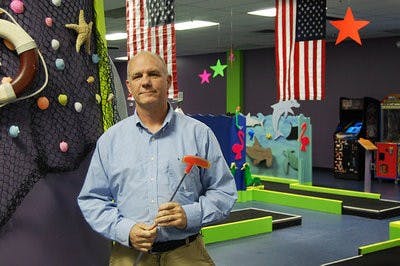 Doug Long stands in his American-themed, 18-hole indoor mini-golf course.