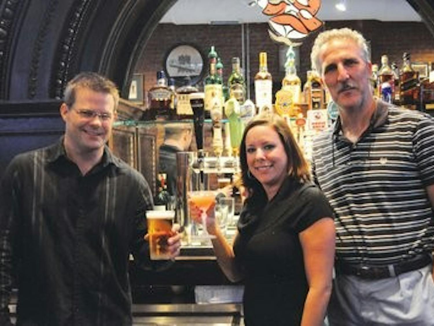 (L-R): General manager Chris McBride and bartender Brooke Mobley toast opening night with co-owner Joseph Garofalo, Monday. (Christen Harned / Assistant photo editor)