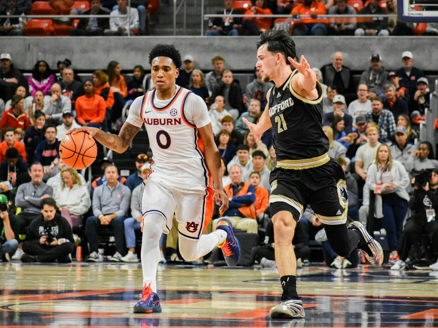Two basketball players are actively engaged in a fast-paced game, with one dribbling a ball while the other is markedly trying to defend.