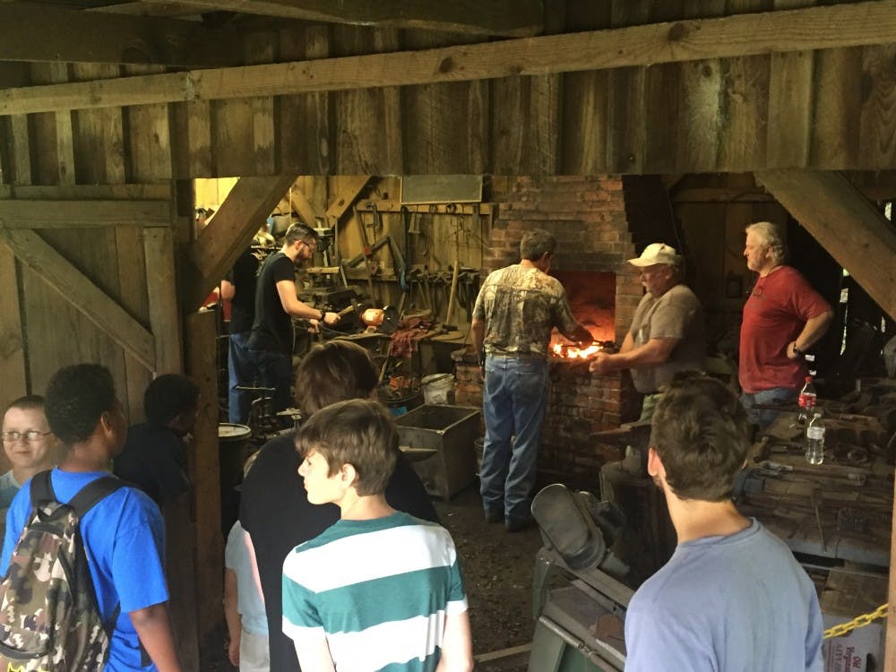 Visitors look on as volunteers work in the Blacksmith Shop in Loachapoka, Ala., on July 7, 2017.