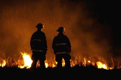 Firefighters look on as flames smolder after a power line fell off S College St.