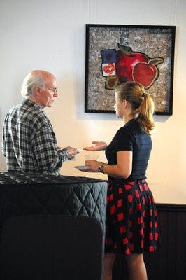Kenneth Walters, retired philosophy professor, listens to Amanda Claire Rives, junior in graphic design and class member, explain one of the pieces in the exhibit. (Christen Harned / Assistant Photo Editor)