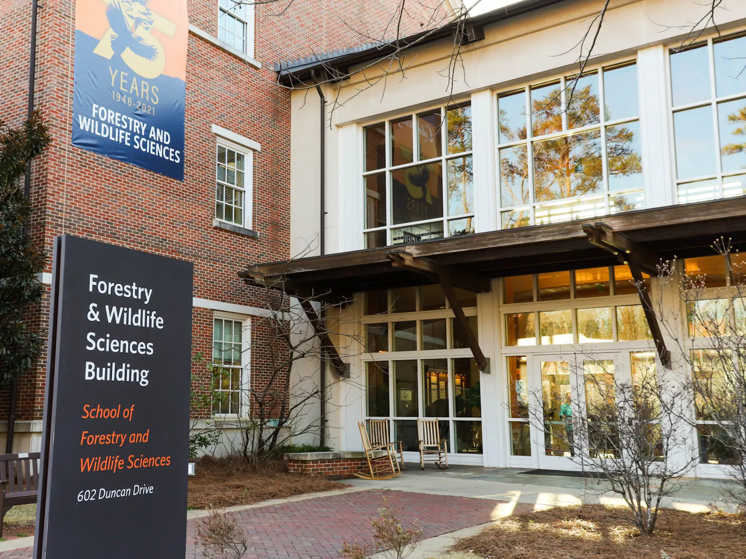 A modern building with large windows features a sign indicating it is the Forestry and Wildlife Sciences Building, surrounded by landscaping.