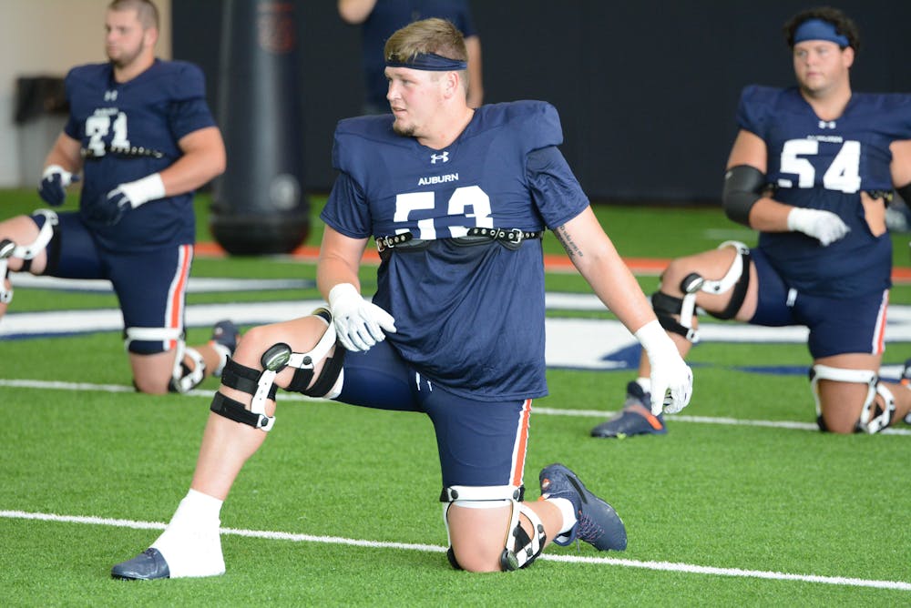 Offensive tackle Gunner Britton stretching at Auburn's football practice at the Woltosz Football Performance Center on Aug. 8, 2023.