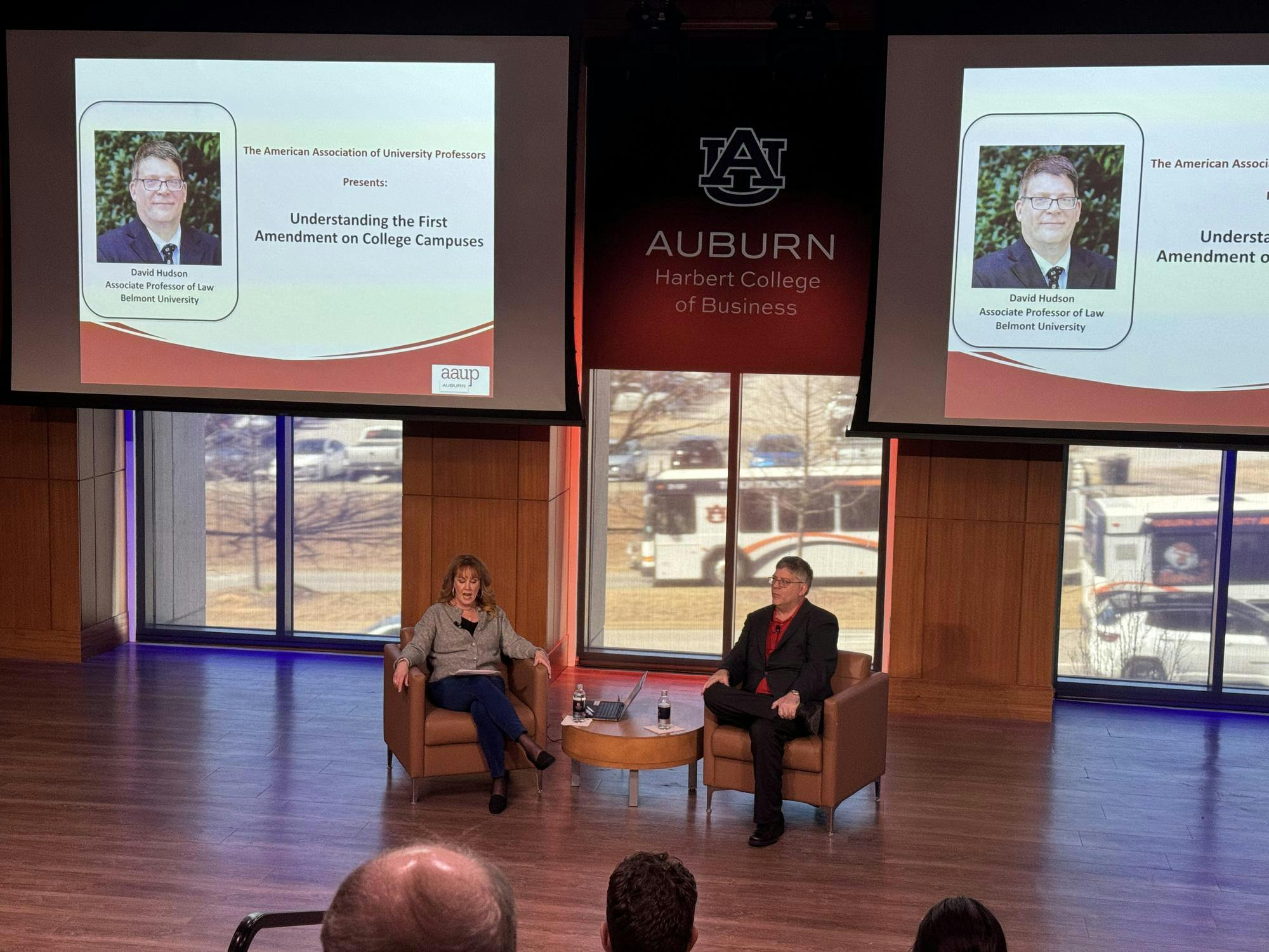 Professor Hudson Jr., and President of the American Association of Professors, Auburn Chapter, Beth Davis-Samrek, sit in front of crowd of professors in Horton Hargrave Hall Auditorium.