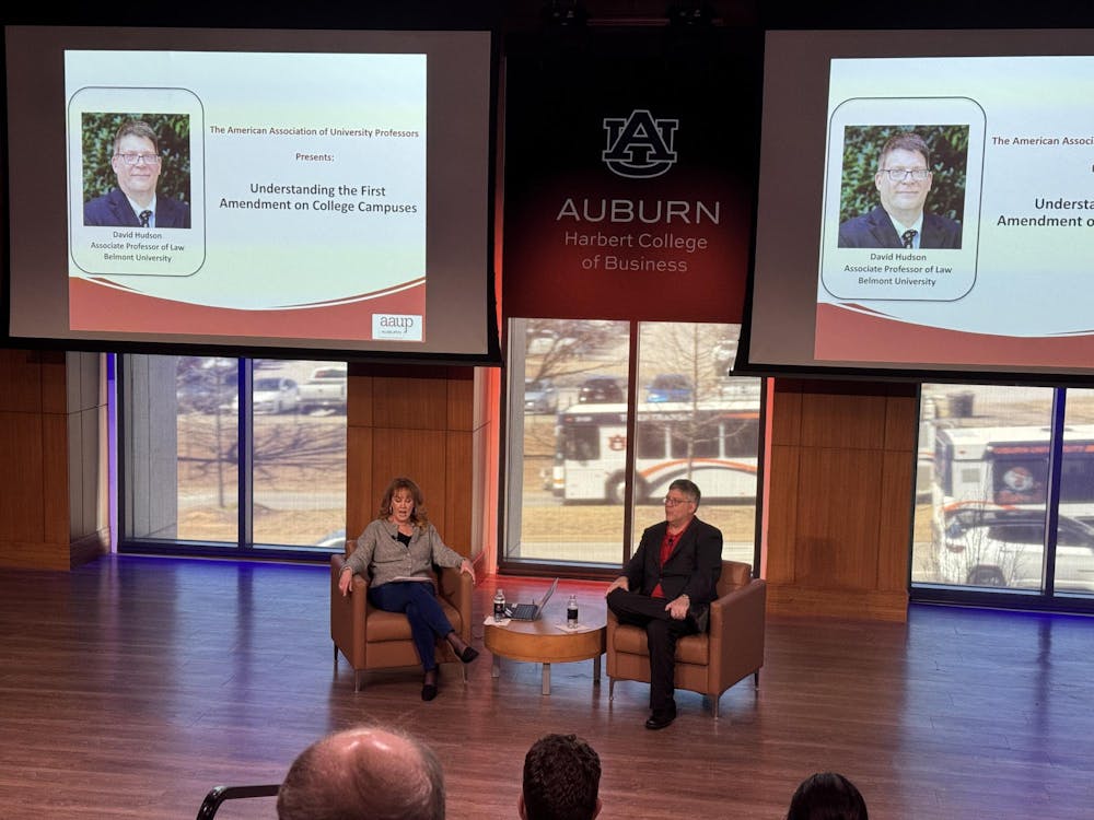 <p>Professor Hudson Jr., and President of the American Association of Professors, Auburn Chapter, Beth Davis-Samrek, sit in front of crowd of professors in Horton Hargrave Hall Auditorium.</p>