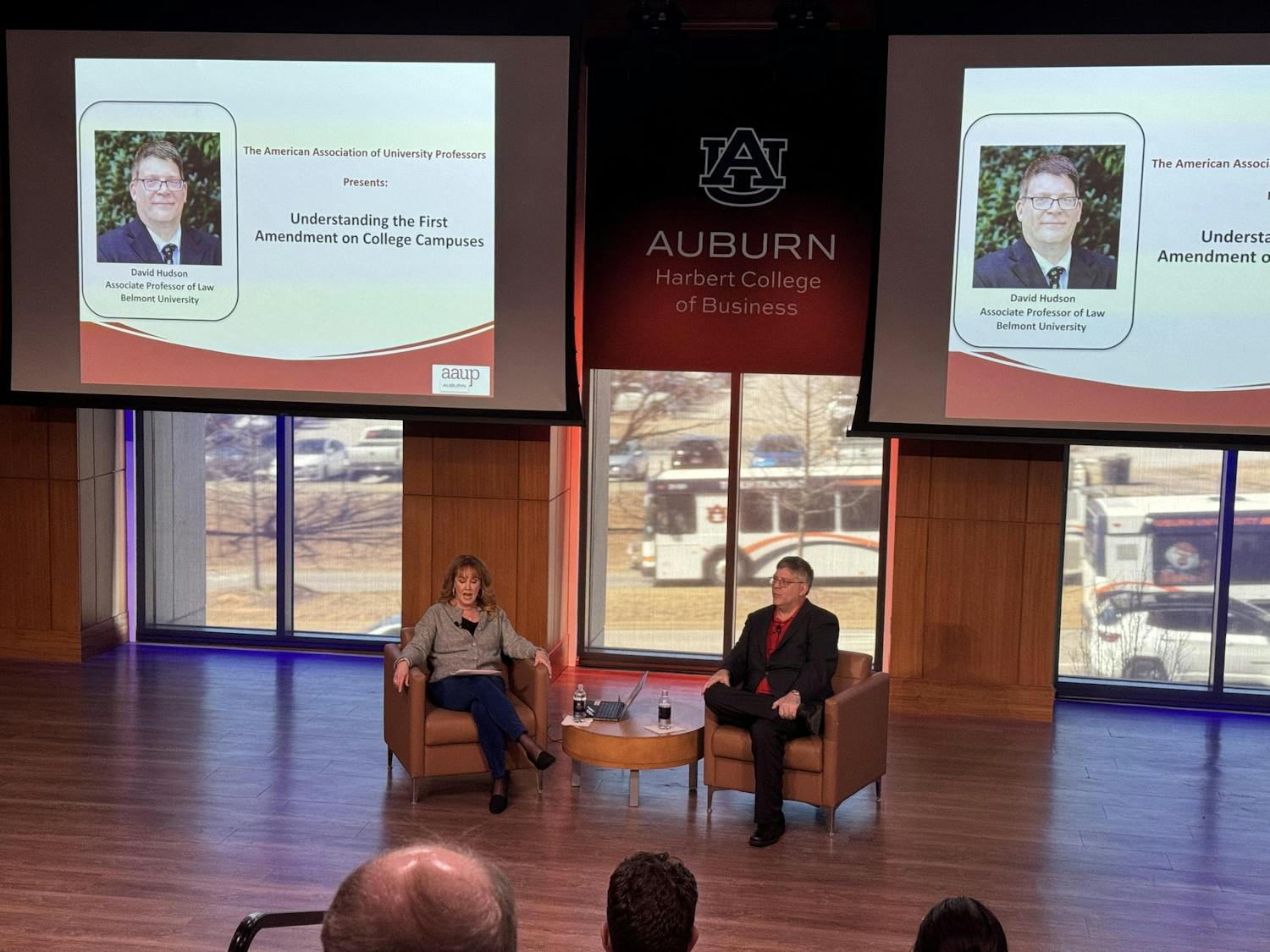 Professor Hudson Jr., and President of the American Association of Professors, Auburn Chapter, Beth Davis-Samrek, sit in front of crowd of professors in Horton Hargrave Hall Auditorium.