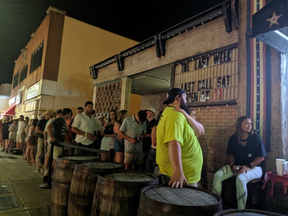 Bar patrons line up outside Quixotes in Auburn, Ala. on Saturday, Aug. 24, 2019.