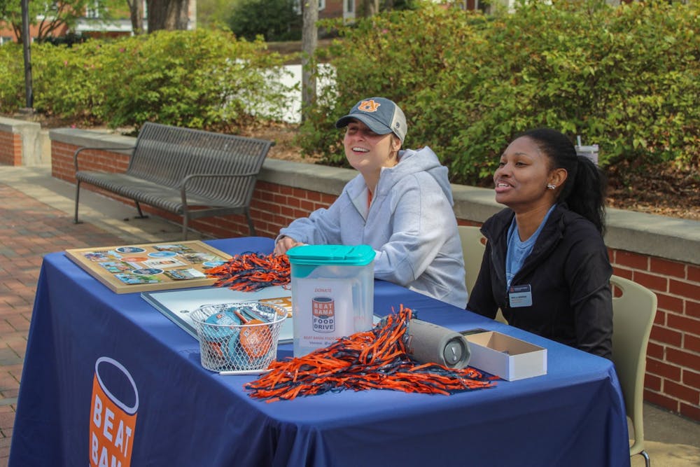 Elly Evans and Mikella Anderson are shown tabling on the concourse for Beat Bama Food Drive.