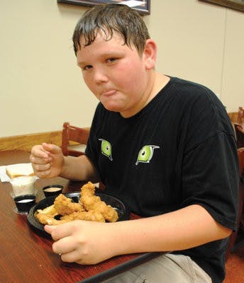 Ryan Johnson, 13, of Drake Middle School, munches on some chicken fingers Sunday at Louie's Chicken Fingers. (Maria Iampietro / Associate Photo Editor)