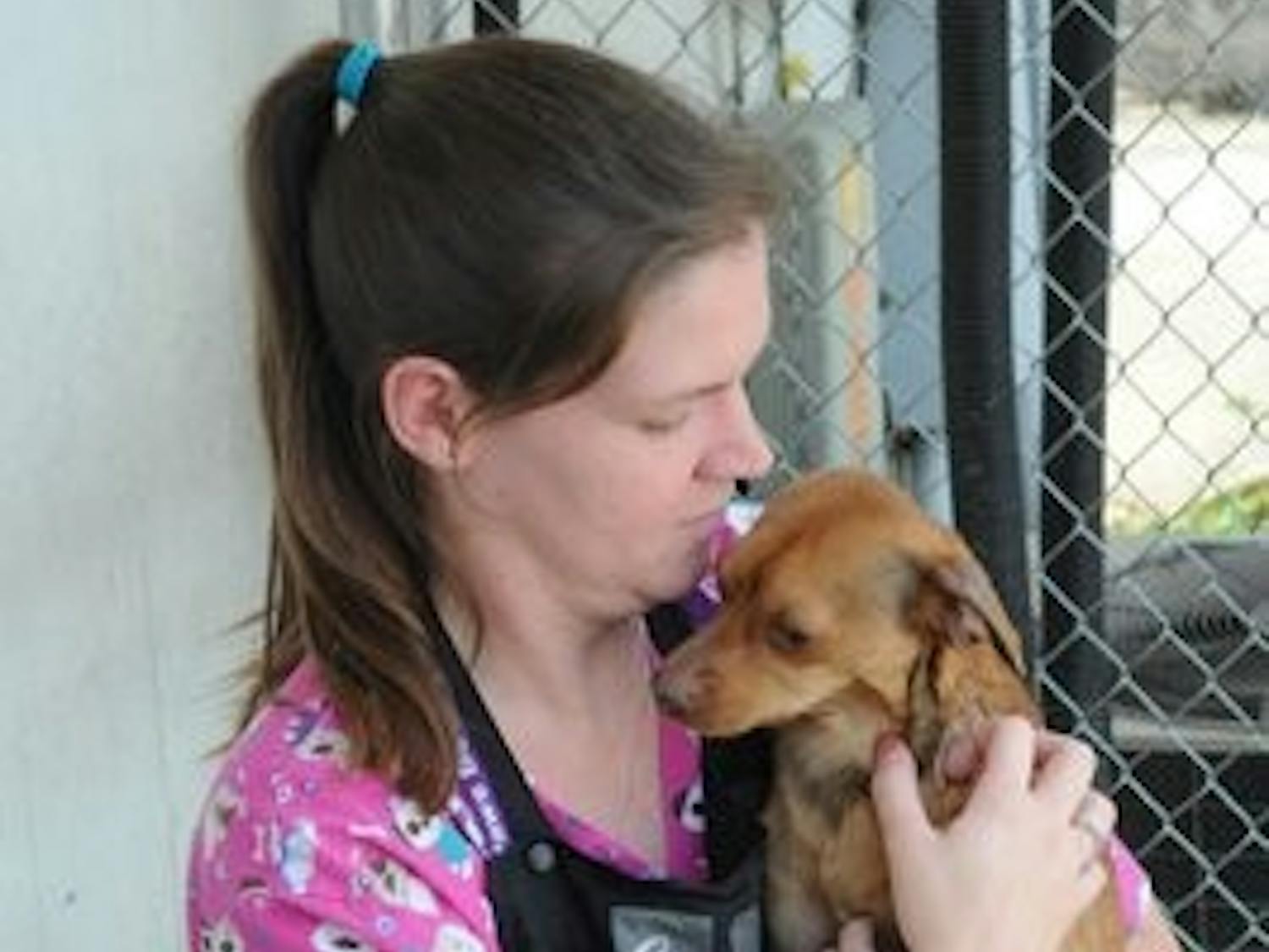 Heather Kather, store and rescue manager, holds Buddy, a 2-year-old adoptable dog. Kather said Buddy makes a great lap dog because he's very affectionate. (Christen Harned / ASSISTANT PHOTO EDITOR)