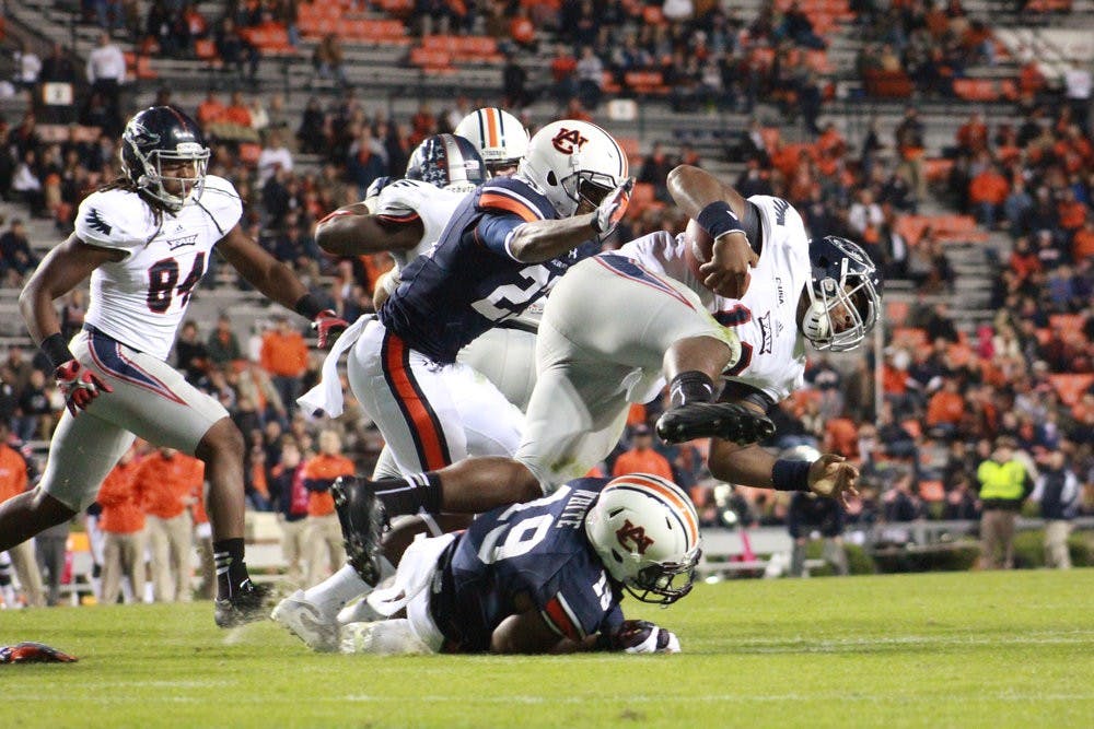 Auburn defensive player Johnathan Ford tackles a FAU player while leaping over Auburn player Ryan White. (Jenna Burgess / ASSOCIATE PHOTO EDITOR)