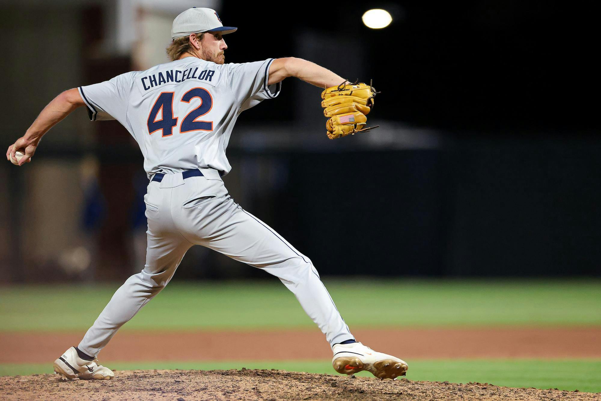 A baseball player in a gray uniform and cap is in a pitching stance on a field, preparing to throw a baseball.