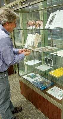 John Varner, a University Archives employee, opens the display case to turn "Jeffrey's Latest 13 More Alabama Ghosts" book to the story about the Auburn Spirit. (Kristen Ferrell / CAMPUS EDITOR)