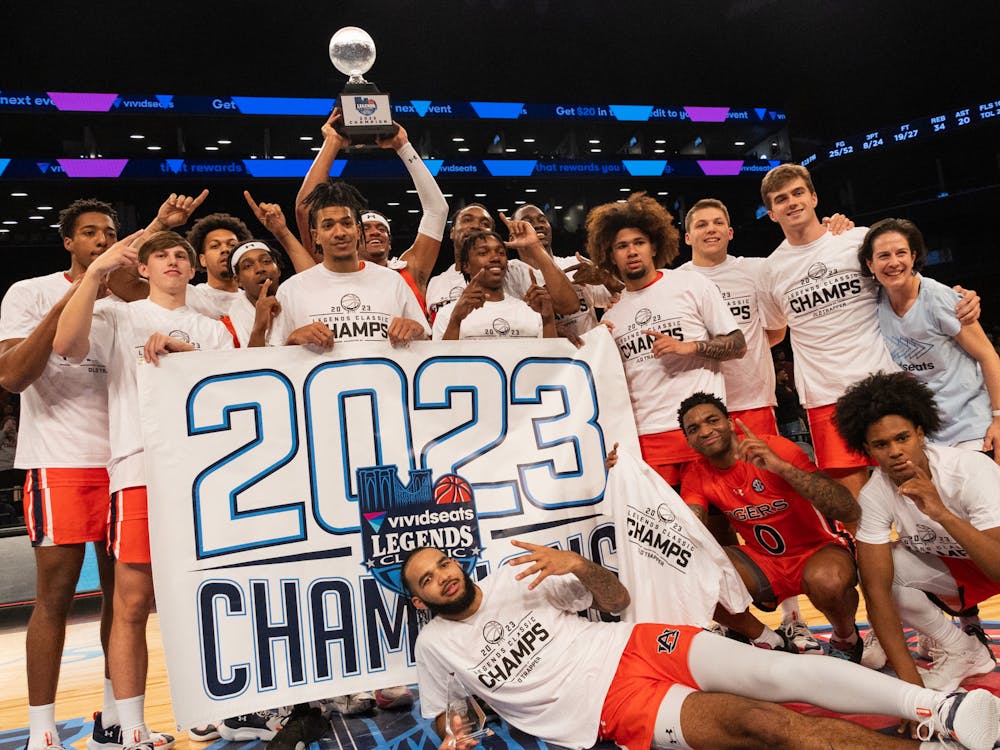The Auburn Men's basketball team celebrates at half court after winning the 2023 Legends Classic