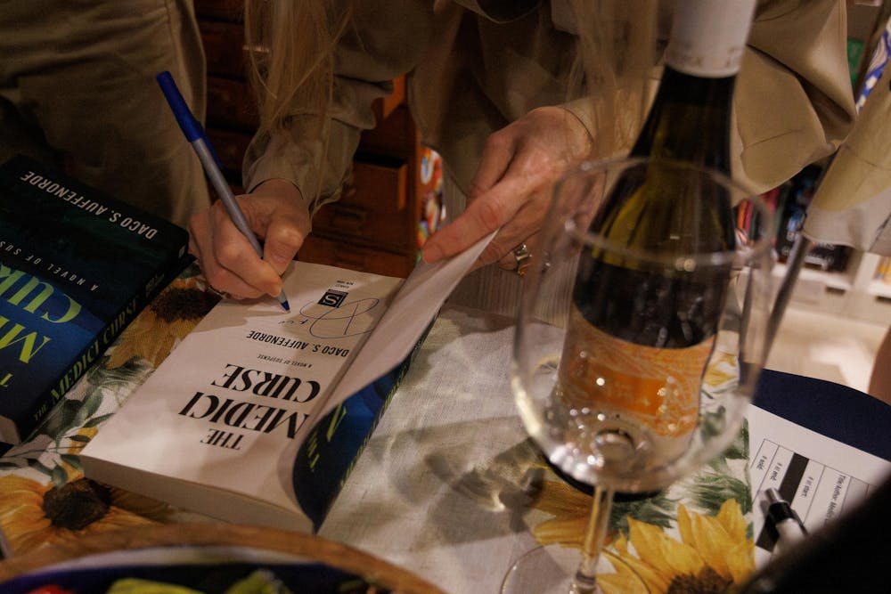Author Daco S. Auffenorde signs a copy of her book during "Page Pairings" at Auburn Oil Co. Booksellers on July 17, 2025.
