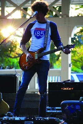 atrick Sweeney, Martha's Trouble guitarist, picks his electric axe as the sun sets in Kiesel Park Thursday. (Kelly Johnson / PHOTO STAFF)