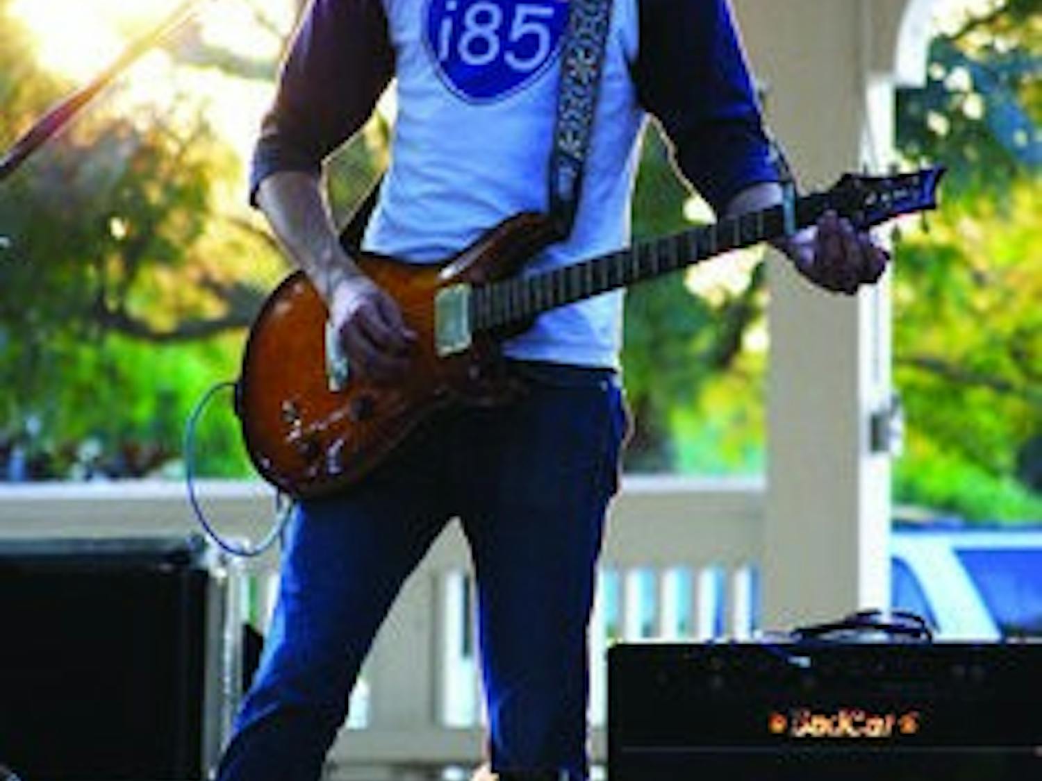 atrick Sweeney, Martha's Trouble guitarist, picks his electric axe as the sun sets in Kiesel Park Thursday. (Kelly Johnson / PHOTO STAFF)