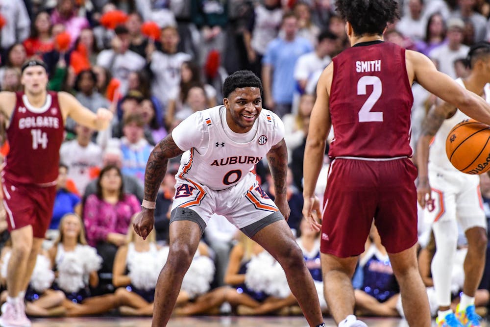 Auburn guard K.D. Johnson (0) shares an expression while guarding an opposing player after hitting a shot against Colgate in Neville Arena on Dec. 2, 2022.