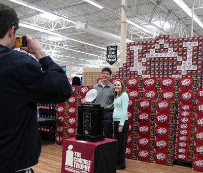 Auburn graduate Michael Riggs and Rebecca Dobson, senior in biomedical science, have their photo taken with the Coaches' Trophy at Walmart Sunday afternoon. (Emily Adams / Photo Editor)