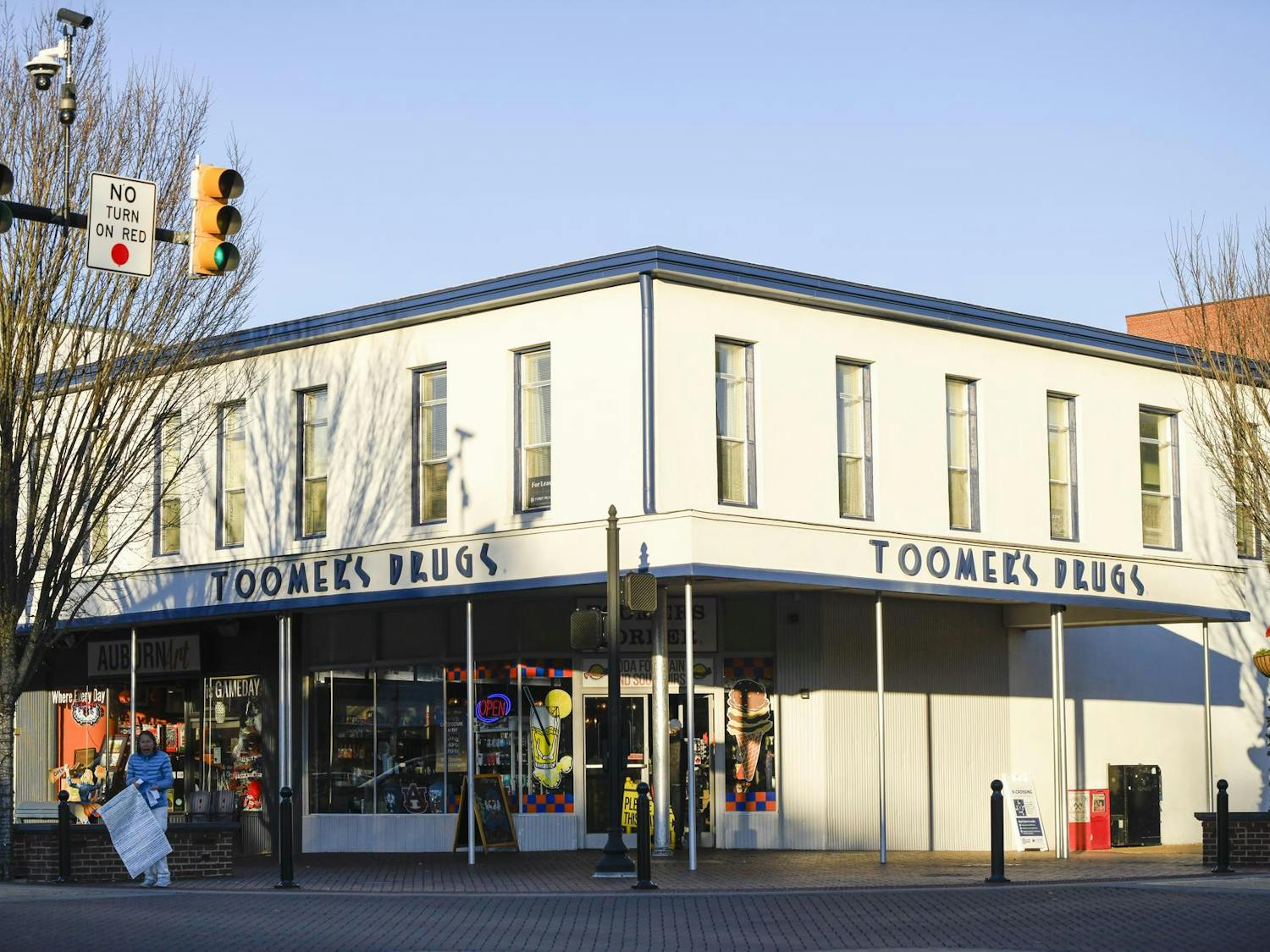 A white building with multiple windows features a pharmacy sign.
