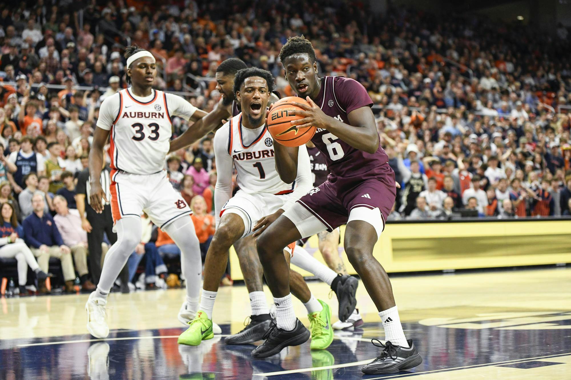 Four basketball players are actively engaged in a play on a court, with one player holding a basketball while others react around him.