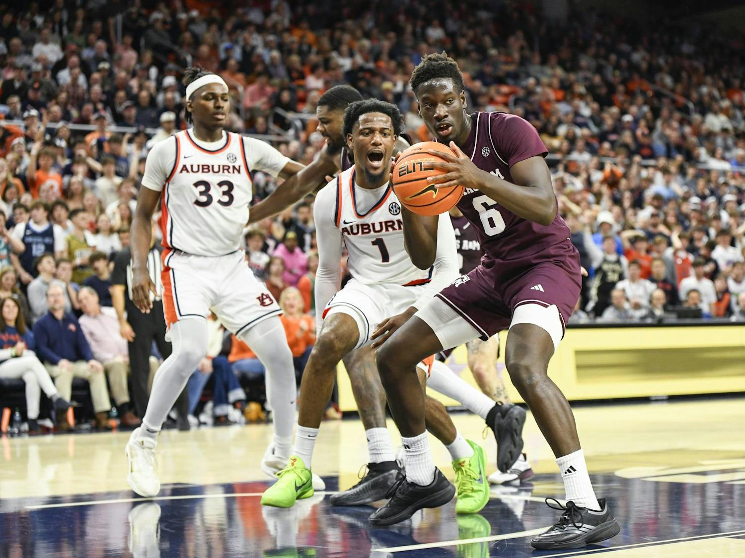 Four basketball players are actively engaged in a play on a court, with one player holding a basketball while others react around him.