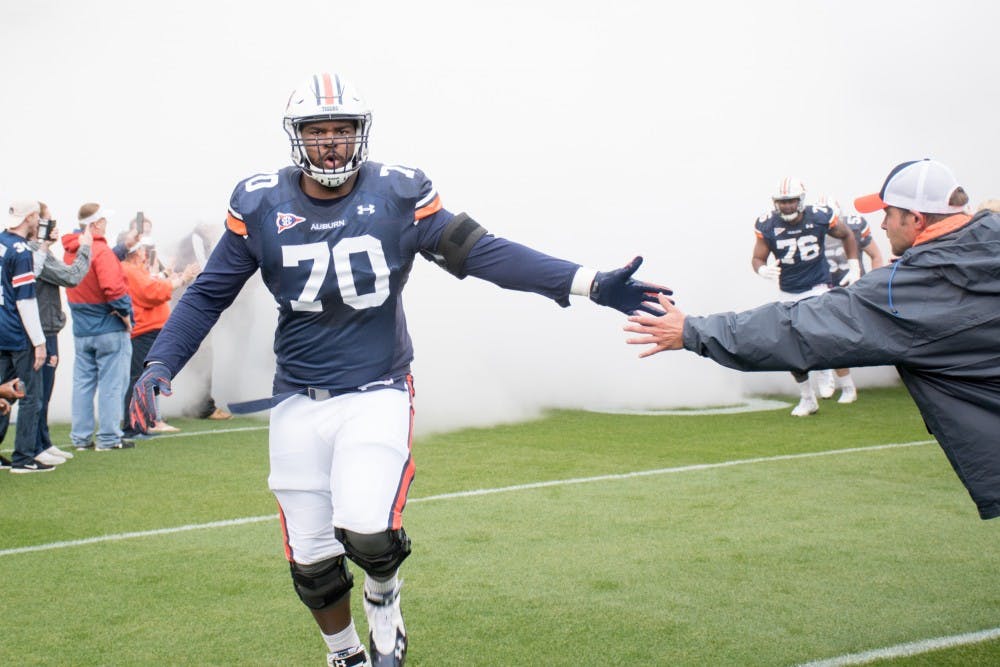 <p>Calvin Ashley (70) high-fives a fan while running out to the field at the A-Day game on Saturday, April 7, 2018, in Auburn, Ala.</p>