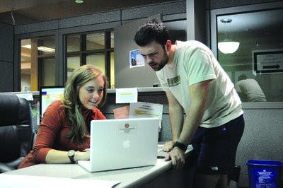 Allison Chandler, IT specialist, takes a look at the computer of Tyler Claxton, junior in forestry. (Christen Harned / ASSISTANT PHOTO EDITOR)