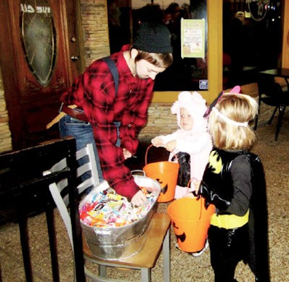 Employees stand outside of stores downtown and offer candy to passing trick-or-treaters. (Contributed by Dana Stewart)