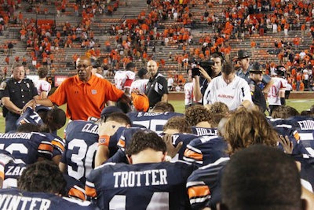 Team Chaplain Chette Williams leads the players in a prayer after the Arkansas State game. (Emily Adams/PHOTO EDITOR)