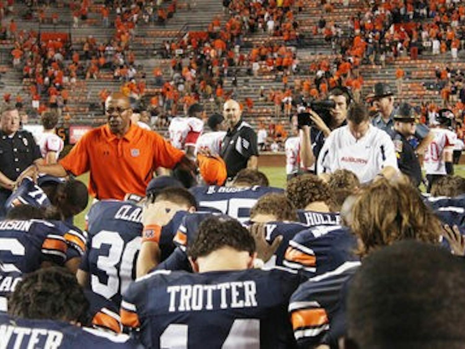 Team Chaplain Chette Williams leads the players in a prayer after the Arkansas State game. (Emily Adams/PHOTO EDITOR)