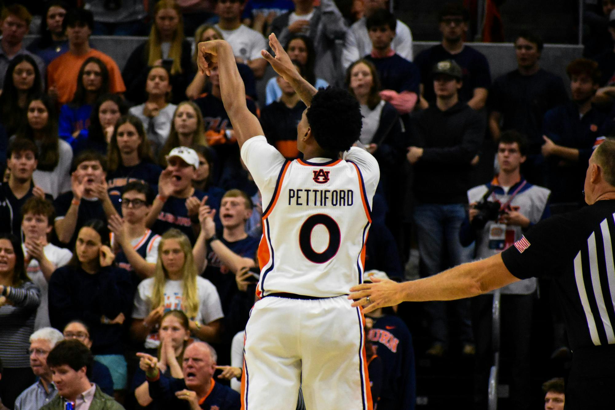 A basketball player, wearing a jersey with "Pettiford" on the back, is shooting the ball, while an excited crowd cheers in the background.