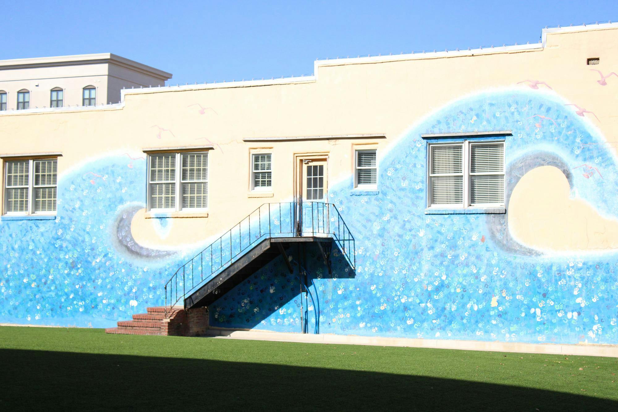 "Wall of Waves" is a mural located on the side of the Beignets & Brews on College St depicting to waves filled with handprints.