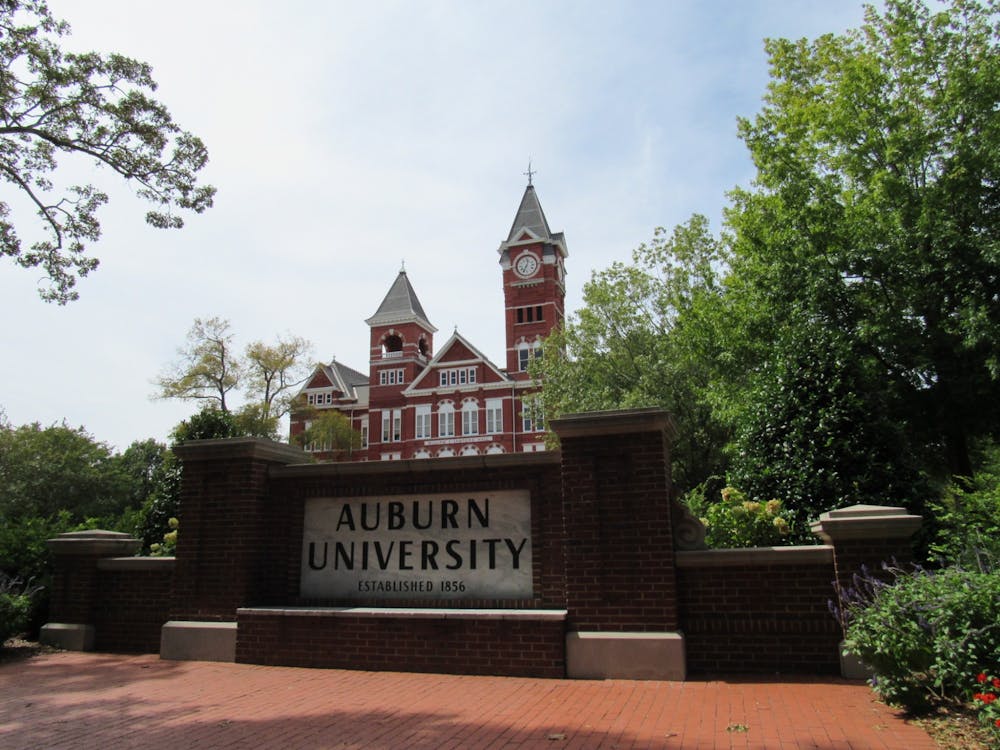 <p>Samford Hall perched behind the Auburn University sign in Auburn, Ala.</p>