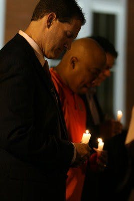 Gene Chizik, left, and Trooper Taylor bow their heads in a moment of silence for former football players Ladarious Phillips and Ed Christian at a candlelight vigil in their honor Thursday night. (Courtesy of Rebecca Croomes)