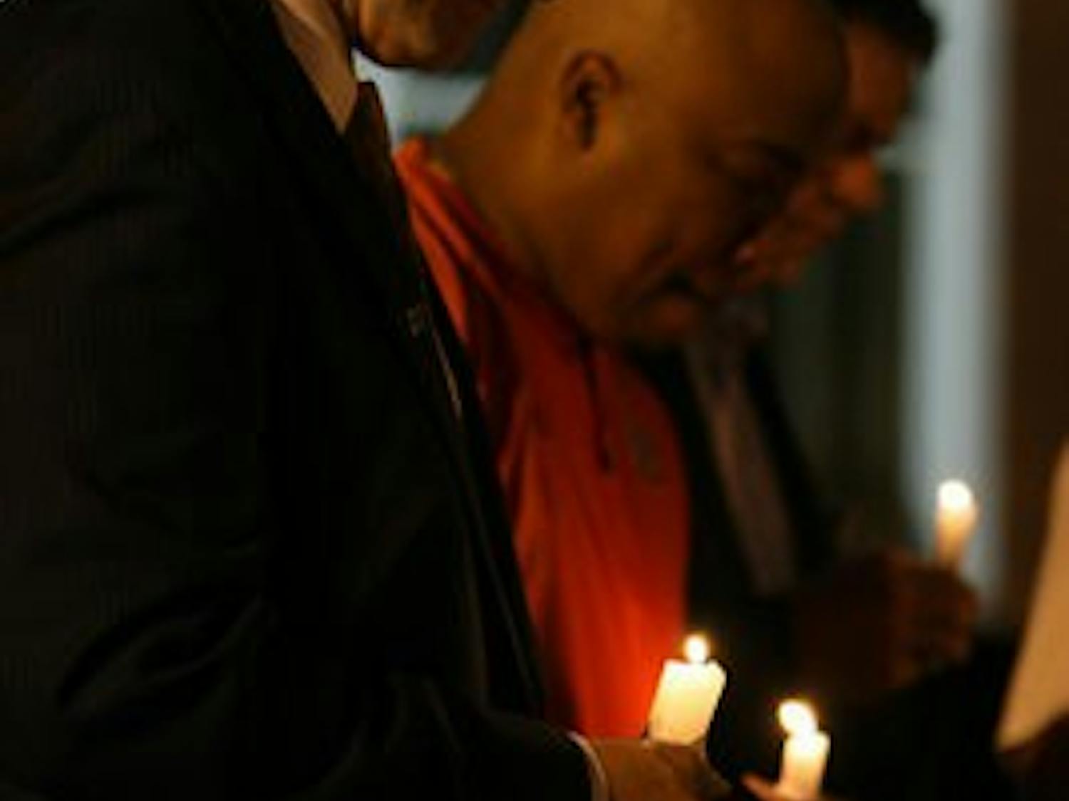 Gene Chizik, left, and Trooper Taylor bow their heads in a moment of silence for former football players Ladarious Phillips and Ed Christian at a candlelight vigil in their honor Thursday night. (Courtesy of Rebecca Croomes)