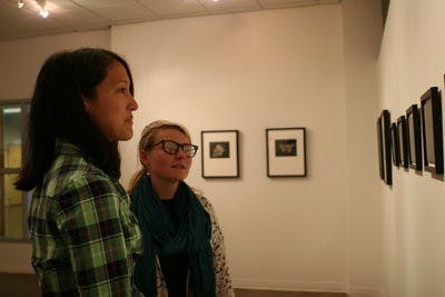 Cyndi Flint, freshman in studio art, and Lawrin Barnard, sophomore in graphic design, discuss subject matter in photographs at the gallery in Biggin Hall Wednesday. (Rebecca Croomes / ASSISTANT PHOTO EDITOR)