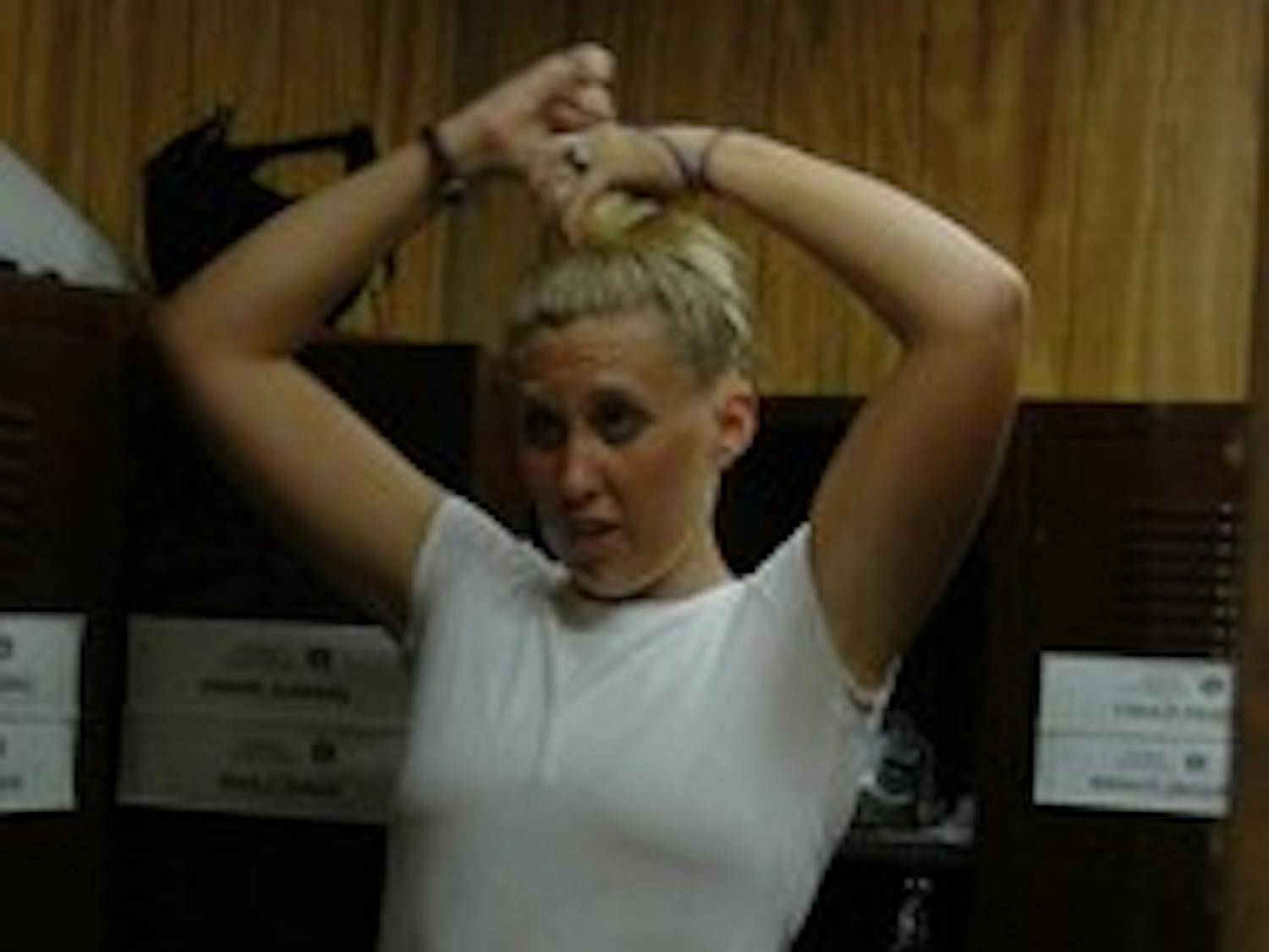 Anna puts her hair up and then covers it with a hair net before she puts on her helmet.