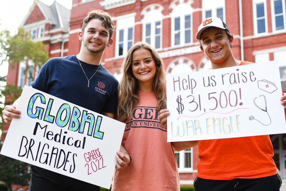 The Auburn Medical Brigade, a chapter of the Global Medical Brigade, holds up signs to raise money for a December trip to Greece on September 1, 2022.
